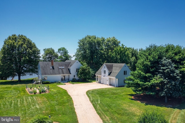 view of front of home featuring a garage, an outbuilding, a chimney, and a front yard