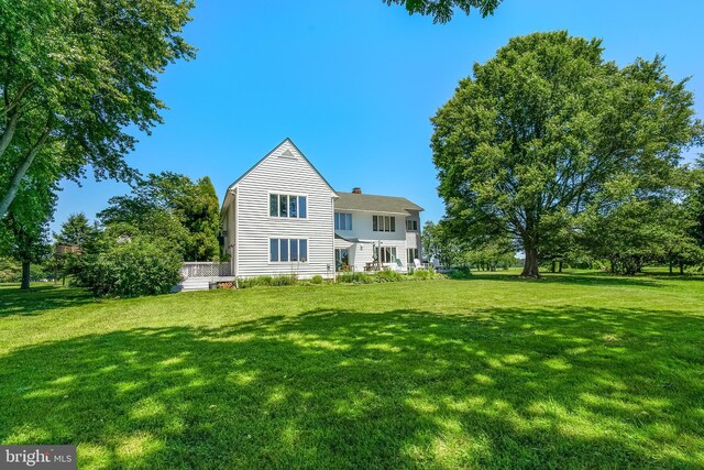 rear view of house with a chimney and a lawn