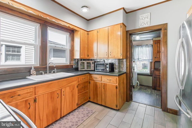 kitchen featuring stainless steel refrigerator, sink, plenty of natural light, and ornamental molding