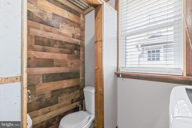 bathroom featuring wooden walls and toilet