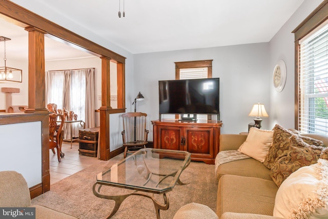 living room featuring a notable chandelier, decorative columns, and light tile floors