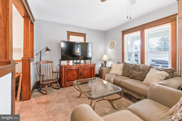 carpeted living room featuring ornate columns and ceiling fan