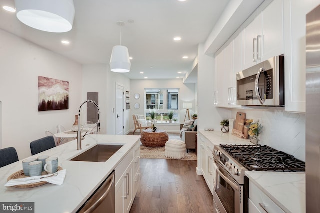 kitchen featuring white cabinetry, light stone countertops, dark wood-type flooring, appliances with stainless steel finishes, and sink