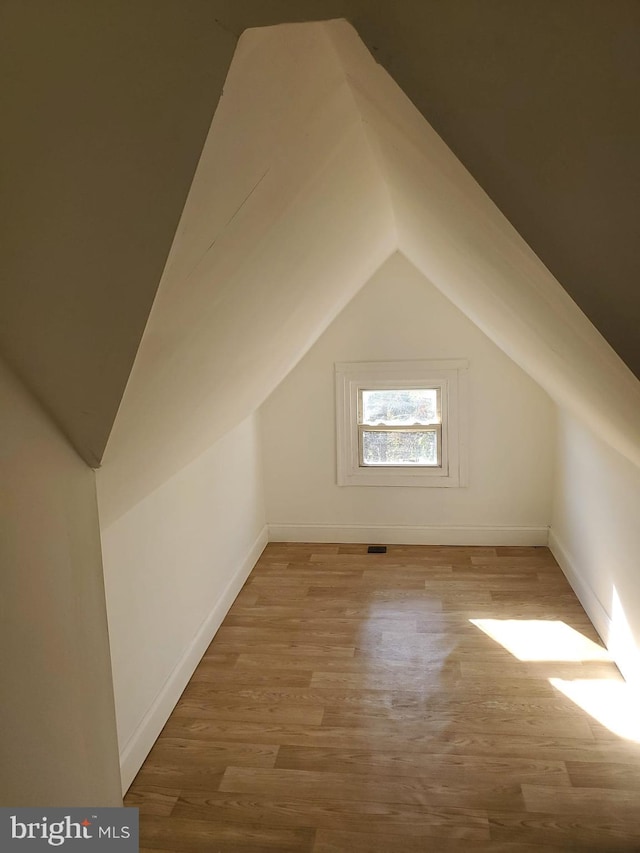 bonus room with hardwood / wood-style floors and vaulted ceiling