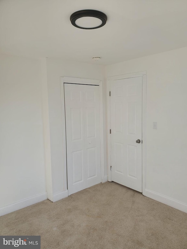 unfurnished bedroom with light carpet and a closet