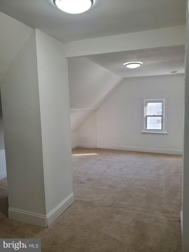 bonus room featuring a textured ceiling, lofted ceiling, and carpet floors