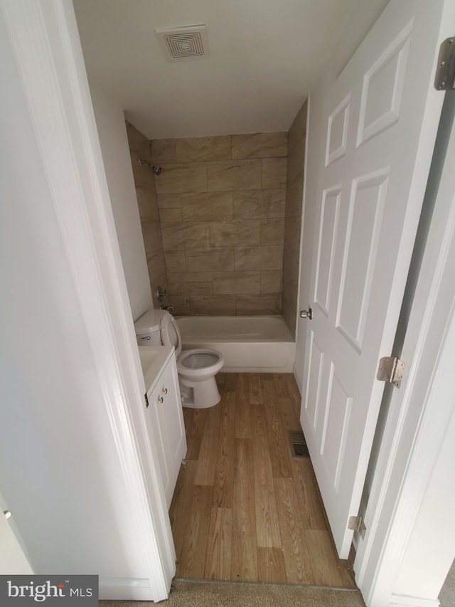 full bathroom with toilet, vanity, tiled shower / bath combo, and hardwood / wood-style flooring