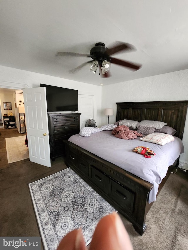 bedroom featuring ceiling fan and dark carpet