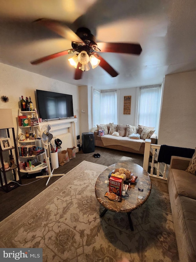 living room featuring ceiling fan and dark carpet