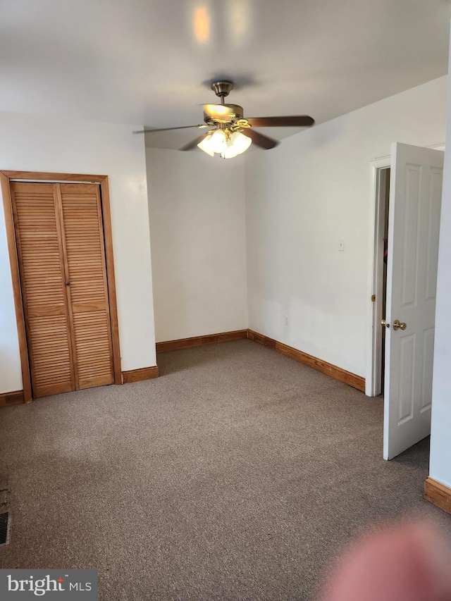 unfurnished bedroom with ceiling fan, a closet, and carpet