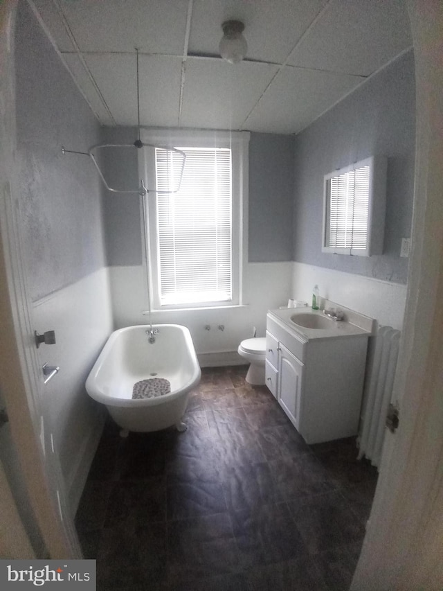 bathroom featuring a tub to relax in, radiator heating unit, vanity, and a drop ceiling