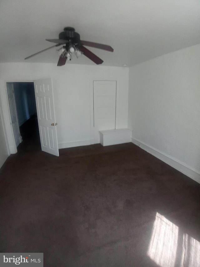 interior space featuring ceiling fan and dark carpet