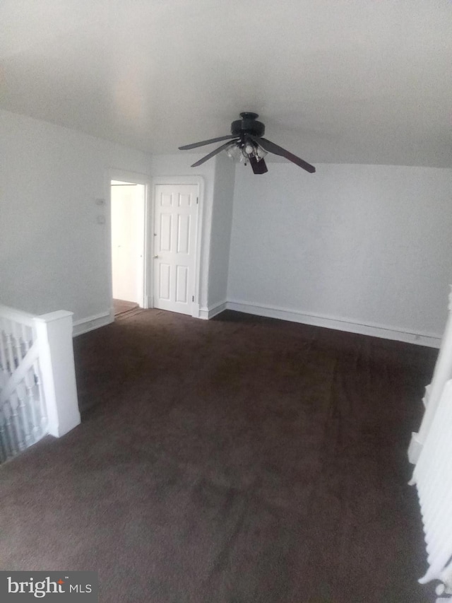 spare room featuring dark carpet and ceiling fan