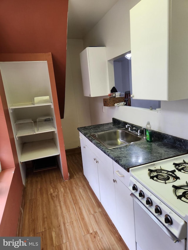 kitchen featuring white gas range oven, light hardwood / wood-style floors, white cabinetry, and sink