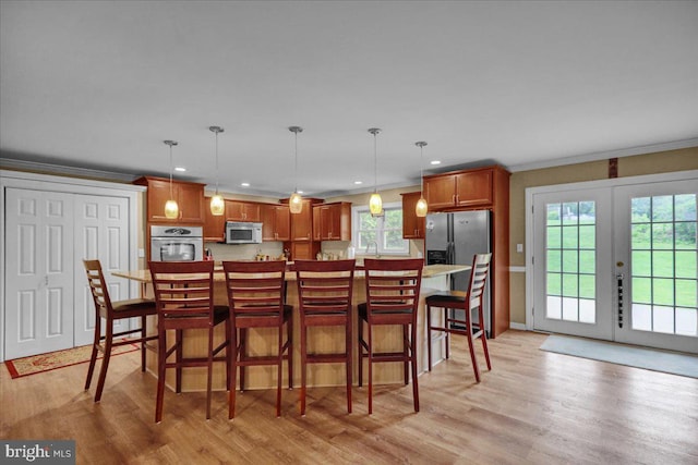 kitchen featuring appliances with stainless steel finishes, a healthy amount of sunlight, french doors, and light hardwood / wood-style flooring