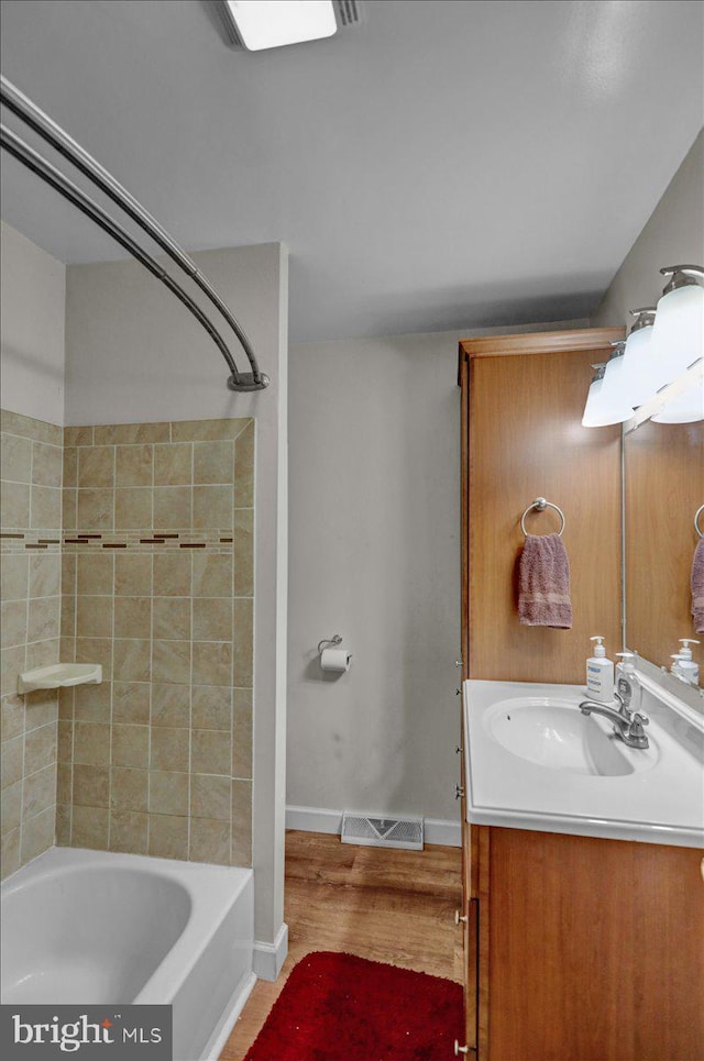 bathroom featuring hardwood / wood-style flooring, vanity, and tiled shower / bath