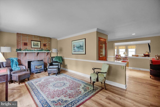 sitting room featuring crown molding, a fireplace, light wood-type flooring, and a wood stove