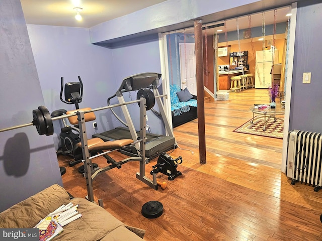 exercise room featuring hardwood / wood-style flooring and radiator heating unit