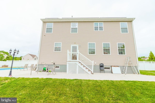 rear view of property featuring a yard, a fenced in pool, and a patio