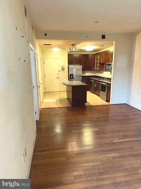 kitchen featuring tile floors, stainless steel appliances, a breakfast bar area, and dark brown cabinetry