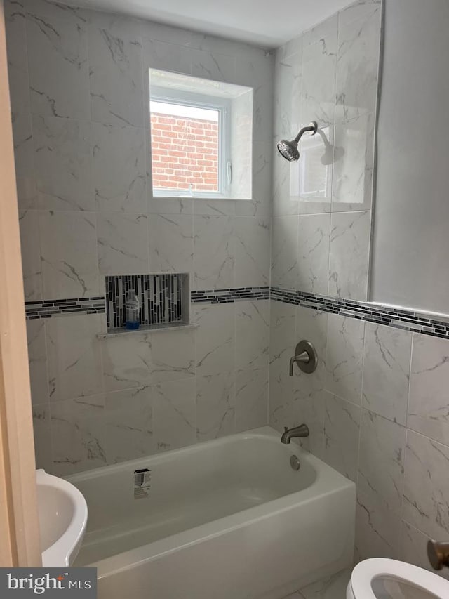 bathroom featuring tiled shower / bath combo and toilet