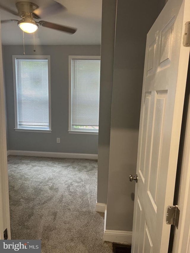 carpeted spare room featuring a healthy amount of sunlight and ceiling fan