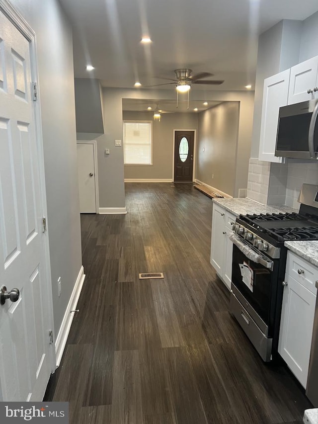 kitchen featuring stainless steel appliances, ceiling fan, tasteful backsplash, white cabinetry, and dark wood-type flooring