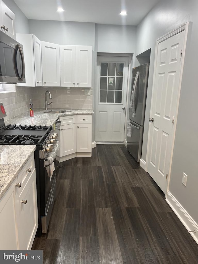 kitchen with appliances with stainless steel finishes, sink, dark wood-type flooring, and backsplash