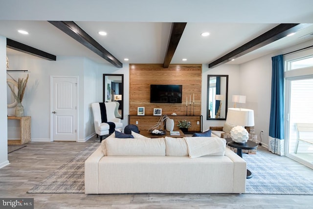 living room featuring beam ceiling, plenty of natural light, and light hardwood / wood-style floors