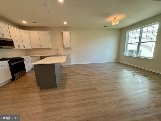 kitchen with appliances with stainless steel finishes, light hardwood / wood-style flooring, white cabinets, and a center island