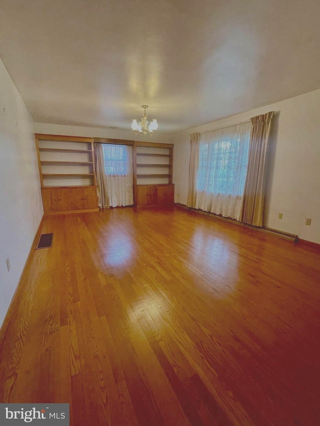 unfurnished living room featuring a notable chandelier and wood-type flooring