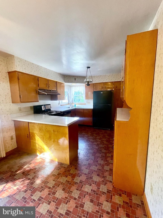 kitchen with sink, kitchen peninsula, decorative light fixtures, black refrigerator, and range