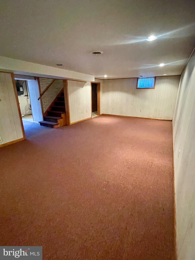 basement with carpet flooring and wood walls