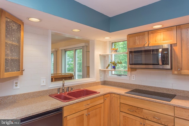 kitchen with light stone counters, black electric cooktop, sink, tasteful backsplash, and dishwasher