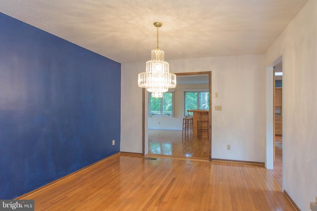 unfurnished room featuring a chandelier and hardwood / wood-style flooring