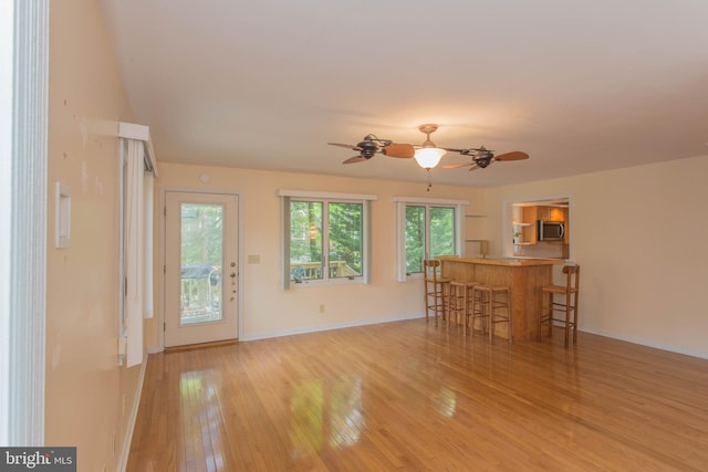 unfurnished living room featuring ceiling fan and light wood-type flooring