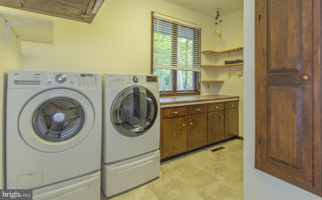 laundry area with washer and clothes dryer, cabinets, and light tile floors