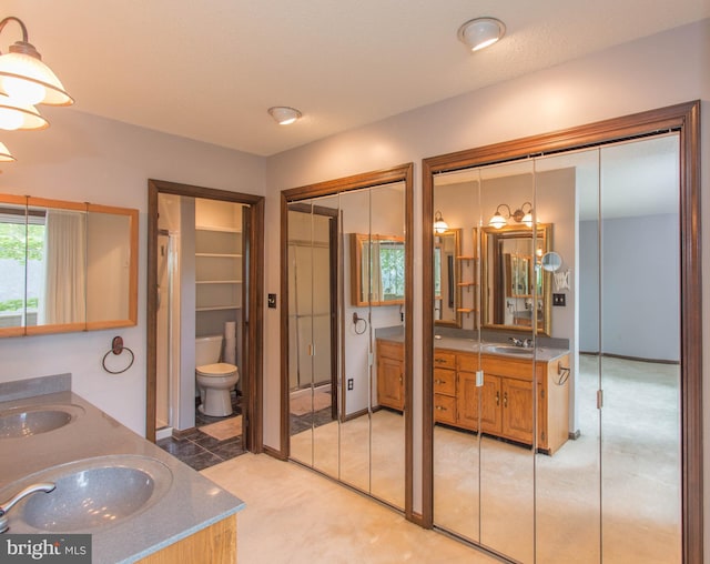 bathroom with dual vanity and toilet