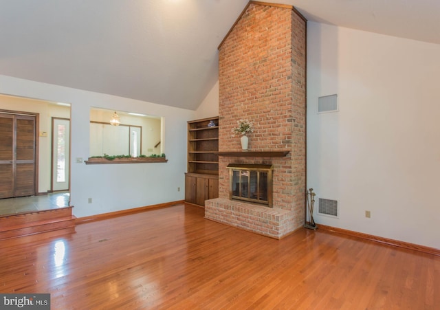 unfurnished living room with a brick fireplace, high vaulted ceiling, brick wall, and wood-type flooring