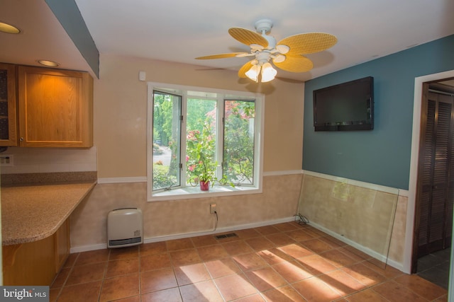 unfurnished dining area with a healthy amount of sunlight, ceiling fan, and tile floors