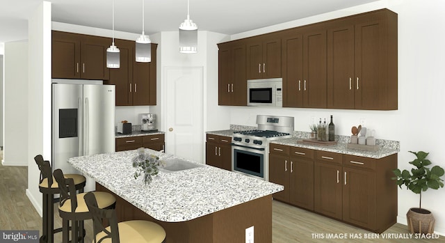 kitchen featuring a center island, stainless steel appliances, decorative light fixtures, and light hardwood / wood-style floors