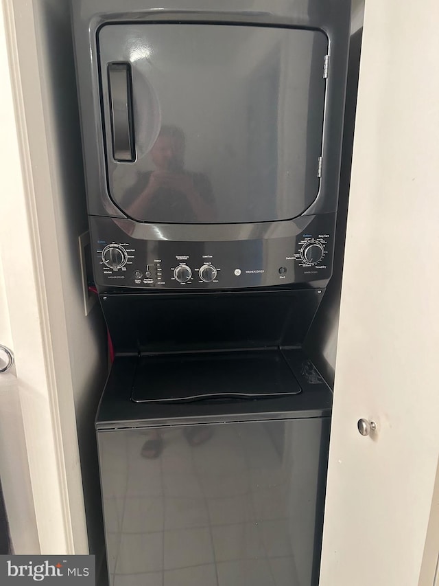 washroom with tile patterned flooring and stacked washer / drying machine