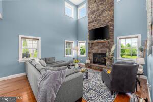 living room featuring plenty of natural light, a towering ceiling, a fireplace, and hardwood / wood-style flooring