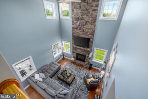 living room featuring a towering ceiling, a fireplace, and wood-type flooring