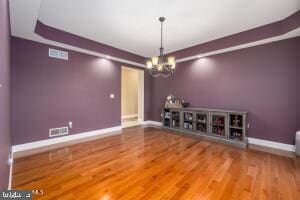 unfurnished dining area featuring a chandelier and hardwood / wood-style flooring