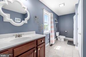 bathroom with tile flooring, toilet, and vanity