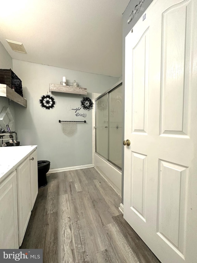 full bathroom with toilet, combined bath / shower with glass door, hardwood / wood-style floors, and vanity