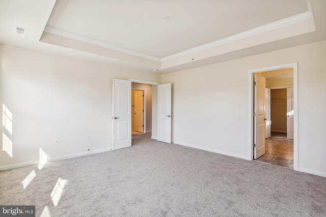 unfurnished room with carpet, ornamental molding, and a tray ceiling