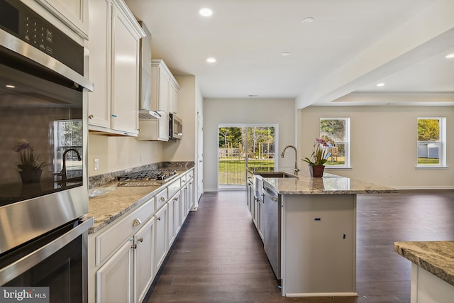 kitchen with stainless steel appliances, white cabinetry, dark hardwood / wood-style floors, and a kitchen island with sink