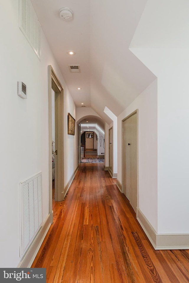 hall with vaulted ceiling and hardwood / wood-style flooring